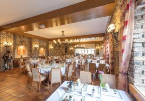 a restaurant with tables and chairs and a brick wall at Sport- und Tagungshotel De Poort in Goch