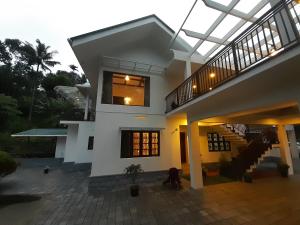 a large white house with a glass roof at Coffee and Pepper Plantation Homestay in Thekkady
