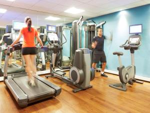 a man and a woman exercising on tread machines in a gym at Novotel Barcelona Sant Joan Despí in Sant Joan Despí