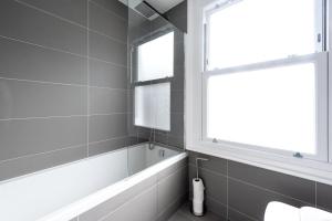 een badkamer met een bad en een raam bij Gorgeous Apartment by Hyde Park (SS4) in Londen