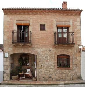 un edificio de ladrillo con 2 balcones y una mesa en Casa Rural El Tenado, en Aldea de Trujillo