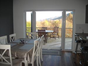 a dining room with a table and chairs and a balcony at Craggan House in Lochearnhead