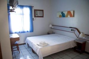 um quarto com uma cama branca e uma janela em Hotel Kloppel em Blumenau