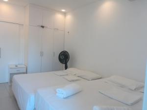 a white room with two beds and a fan at EmanuelleSales - Corretora de Imóveis - "LUXURY RESIDENCES" creci 16949F in Canoa Quebrada