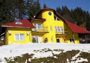 una casa gialla con tetto rosso nella neve di Agata a Wisła
