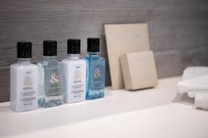three bottles of soap and towels on a bathroom counter at Hotel Juliani - Boutique Hotel in St. Julianʼs