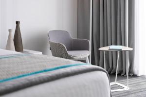 a bedroom with a chair and a side table at Hotel Juliani - Boutique Hotel in St. Julianʼs