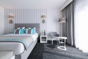 a white bedroom with a bed and a chair at Hotel Juliani - Boutique Hotel in St. Julianʼs