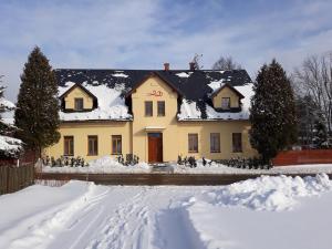 una casa gialla con neve per terra di Penzion Červená voda -penzion s dotekem dálek a Červená Voda