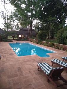 a swimming pool with two lounge chairs next to it at Simbamwenni Lodge and Camping in Morogoro