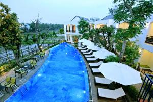 a pool at a hotel with chairs and umbrellas at Azumi in Hoi An