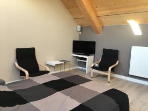 una camera con 2 sedie, una TV e un letto di Ecolodge Otra Cosa a Mouscron