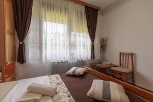 um quarto com uma cama e uma janela com uma cadeira em Plitvice House Milan em Jezerce