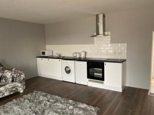 COACHMAN COTTAGE OUTSIDE HOT TUB في Beith: مطبخ مع غسالة ومجفف في الغرفة