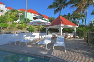 um deque com cadeiras e guarda-sóis ao lado de uma piscina em Les Ilets De La Plage em Gustavia