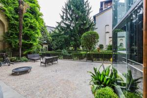 un patio con bancos, una mesa y un edificio en Altana Bergamo Home, en Bérgamo