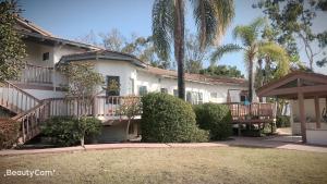 a white house with a porch and palm trees at Rancho Garden Home in Rancho Santa Fe