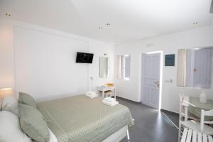 a white bedroom with a bed and a table at Santorini View Studios - Firostefani Caldera in Firostefani