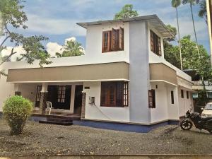 a white house with a motorcycle parked in front of it at Snehatheeram Homestay in Alleppey