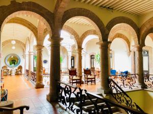 Habitación grande con arcos, mesas y sillas. en Hotel Herencia By Hosting House en Morelia