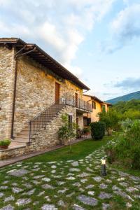 a stone house with a staircase in a yard at Relais Parco Del Subasio in Piano Delle Pieve
