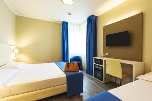 a hotel room with two beds and a desk at Hotel Oleggio Malpensa in Oleggio