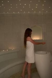 a woman in a white dress standing next to a bath tub at Grand TheoNi Boutique Hotel & Spa in Vasiliki