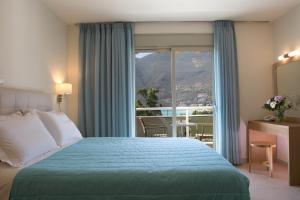 a hotel room with a bed and a large window at Grand TheoNi Boutique Hotel & Spa in Vasiliki