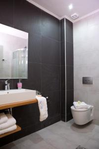 a bathroom with a sink and a toilet and a mirror at Grand TheoNi Boutique Hotel & Spa in Vasiliki