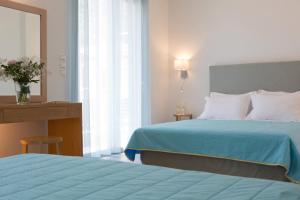 a hotel room with two beds and a mirror at Grand TheoNi Boutique Hotel & Spa in Vasiliki