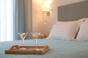 two glasses of wine on a tray on a bed at Grand TheoNi Boutique Hotel & Spa in Vasiliki