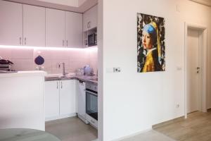 a kitchen with white cabinets and a painting on the wall at Apartman Niki in Arandelovac