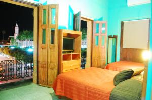 a bedroom with a bed and a television and a balcony at Hotel Santa Elena in El Fuerte