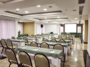 a conference room with green tables and chairs and a screen at Sol Alphaville Hotel & Residence in Barueri