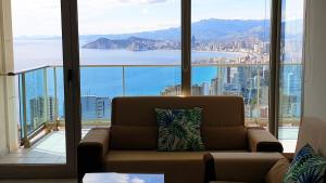 a living room with a couch in front of a large window at Torre Lugano Sea Views (Floor 28th) in Benidorm