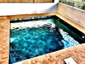 a swimming pool with a tile floor and blue water at VILLA CAMPANA - Bastia centre in Bastia