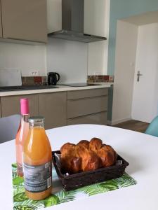 a table with a bottle of orange juice and a basket of chickens at La Palmeraie - Appartement classé 4 étoiles - Hyper centre ville in Quimper