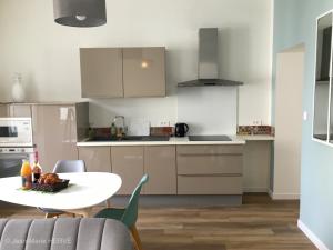 cocina con armarios blancos, mesa y sillas en La Palmeraie - Appartement classé 4 étoiles - Hyper centre ville, en Quimper