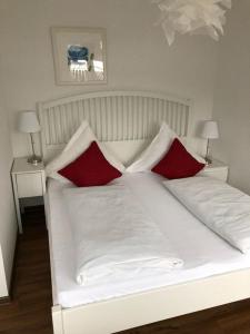 a white bed with two red pillows on it at Ferienwohnung Stadtflair in Daun