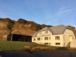 una grande casa bianca con una montagna sullo sfondo di Guesthouse Carina a Vík