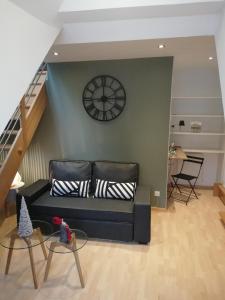 a living room with a couch and a clock on the wall at Atelier des Poèmes. in Montbéliard