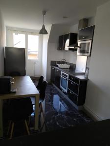 uma cozinha com uma mesa e um fogão forno superior em Bel appartement en plein coeur de ville em Le Creusot