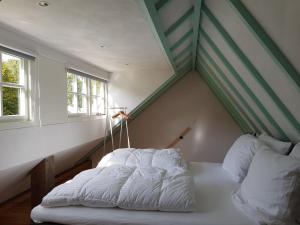 een bed in de hoek van een kamer met 2 ramen bij De Cromvoirtse Bed and Breakfast in Cromvoirt