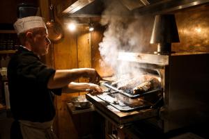 a man cooking food over a grill in a kitchen at La Tambra - Residence - Central with Restaurant in Santa Cristina Gherdëina
