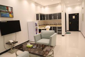 a living room with a white chair and a television at Quiet Rooms Suites By Quiet Rooms in Riyadh