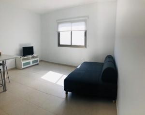 Una sala de estar con un sofá negro y una mesa. en Suite ladybird, en Breña Baja