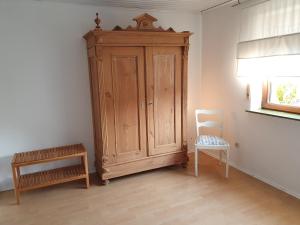 a wooden cabinet and a chair in a room at Ferienwohnung Urlaub im Kraichgau in Sinsheim