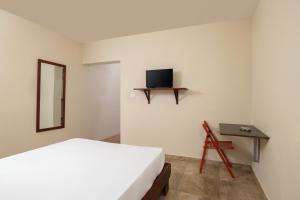 a bedroom with a bed and a tv on the wall at Hotel Bocaino in Yuma