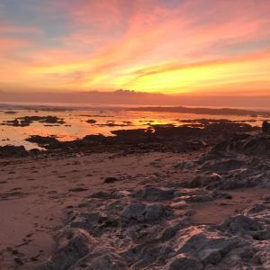 a sunset on a beach with rocks in the water at Casa da Fátima, in Vila Chã
