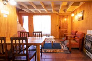 a dining room with a table and chairs and a couch at Cabañas La Posada in Puerto Montt